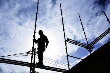 A building worker "steeplejack" assembling the scaffold at the housing construction site : Framework construction