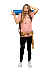 Full body Young backpacker woman pointing finger to the side and presenting a product on isolated background
