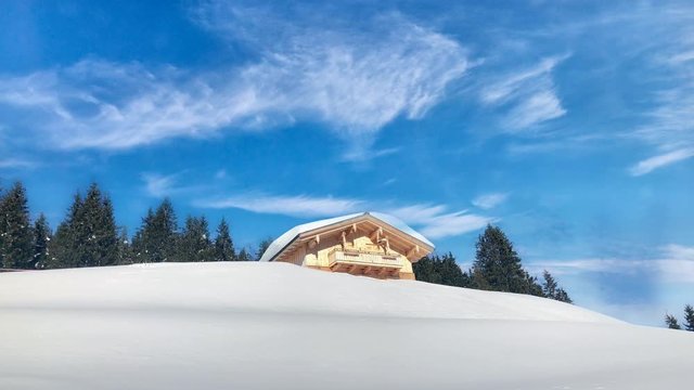 Snow covered chalet or alpine cottage in the mountains agsinst great blue sky