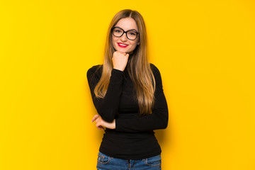 Young pretty woman over yellow background with glasses and smiling