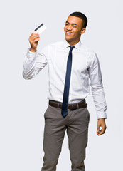 Young afro american businessman holding a credit card and thinking on isolated background