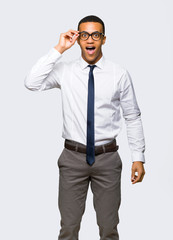 Young afro american businessman with glasses and surprised on isolated background
