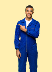 Fototapeta premium Young afro american worker man pointing to the side to present a product on isolated background