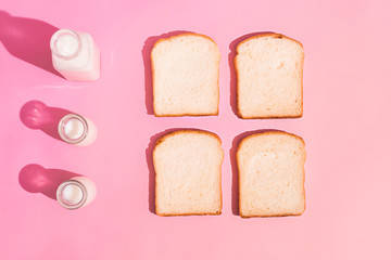 A slice of rye bread and milk on a  pink background