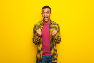 Young afro american man on yellow background celebrating a victory in winner position