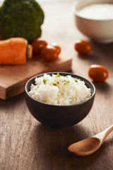 Grains of rice in a wooden bowl and ingredients for a vegetarian recipe - healthy eating concept