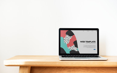 Laptop showing website template on a wooden table