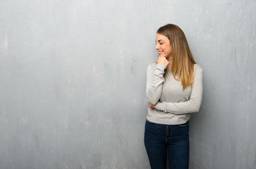 Young woman on textured wall looking to the side with the hand on the chin