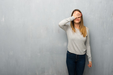 Young woman on textured wall covering eyes by hands. Do not want to see something