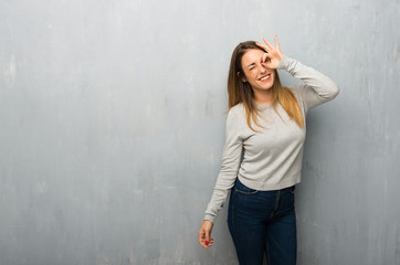 Young woman on textured wall makes funny and crazy face emotion
