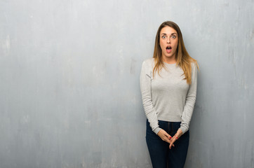 Fototapeta premium Young woman on textured wall with surprise and shocked facial expression
