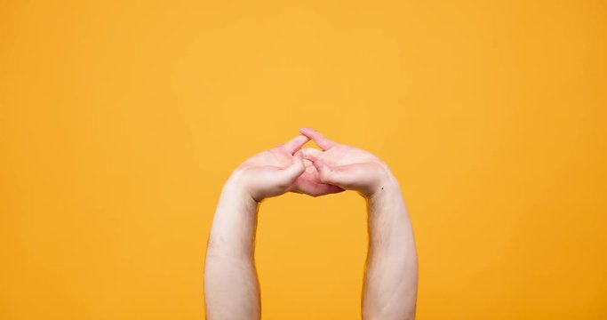 Hands making different silly signs isolated on yellow orange background in studio