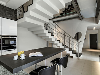 interiors shots of a modern kitchen in the foregroundt he dining table and the forehrounf  the masonry staircase
