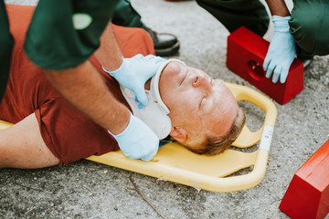 Paramedic team  placing a cervical collar to an injured man - Powered by Adobe