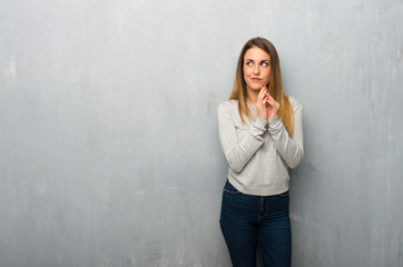 Young woman on textured wall scheming something