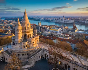 Muurstickers Boedapest, Hongarije - de belangrijkste toren van het beroemde Vissersbastion (Halaszbastya) van bovenaf met Parlementsgebouw en rivier de Donau op de achtergrond op een zonnige ochtend © zgphotography