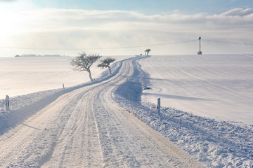 Verschneite Straße bei Sonnenaufgang
