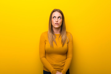 Obraz premium Young woman on yellow background with confuse face expression while bites lip