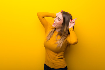 Young woman on yellow background makes funny and crazy face emotion
