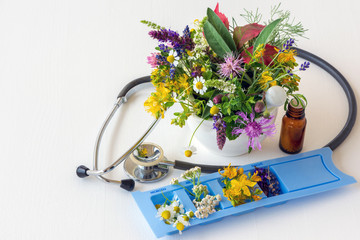 Konzept Alternativmedizin: Stethoskop mit Tablettenspender, Globuli und diversen Heilpflanzen © Sonja Birkelbach