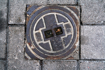 Scandinavian manhole in its urban surrounding.  Hidden beauty in design, texture, colors, shape and pattern of a sewer cover 