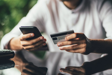 Close up shot of man's hands holding mobile and credit card. businessman checking account balance, using online banking application on his cell phone