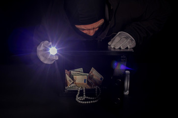 thief stealing valuables from safe at crime scene