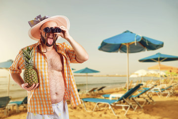 Funny fat bearded man with binoculars on vacation in  the beach in summer. 