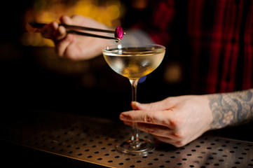 Barman hand decorating elegant cocktail with a little rose bud