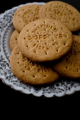 Close up digestive cookies biscuit on white vintage plate on black background with copy space 