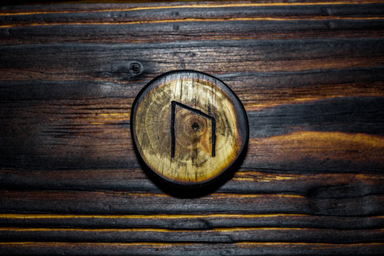 Rune Ur (Uruz) carved from wood on a wooden background - Elder Futhark