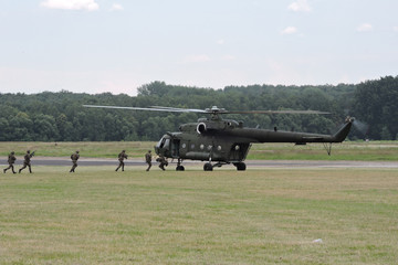 Soldiers getting in a military helicopter and lying on the ground during air show in Poland