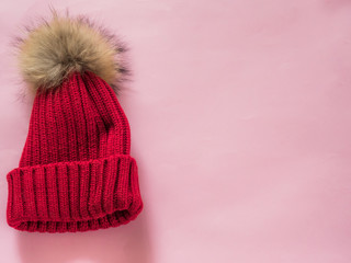 Red wool hat on pink background with copy space