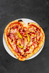 Heart shaped pizza with meat and vegetables. Food concept of romantic love for Valentines Day.