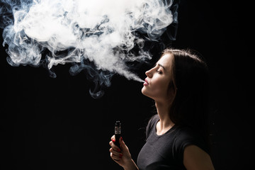 Young woman smoking electronic cigarette isolated on dark background