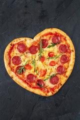 Heart shaped pizza with meat and vegetables. Food concept of romantic love for Valentines Day.