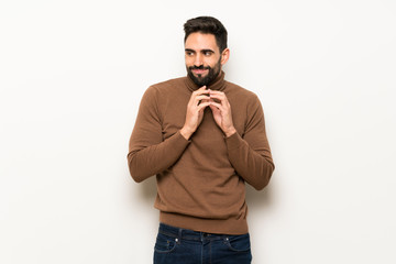 Handsome man over white wall scheming something