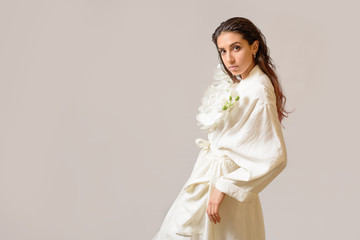 Portrait of Sensual Woman in white dress holding a white orchid against white background. Copy Space