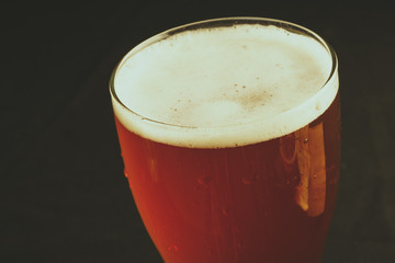 A glass of beer on a black background, close-up