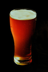 A glass of beer on a black background, close-up