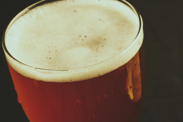 A glass of beer on a black background, close-up