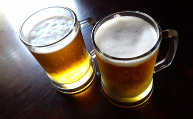 Two frothy glasses of draft beer on the table upper view