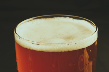 A glass of beer on a black background, close-up