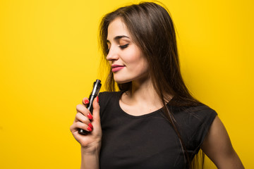 Young woman holding vape isolated on yellow background
