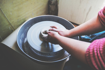 Child hands working with clay on pottery wheel