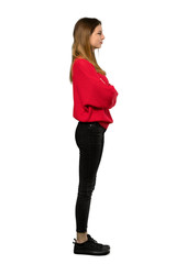 A full-length shot of a Young woman with red sweater in lateral position over isolated white background