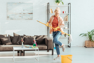 Gorgeous senior woman dancing while cleaning floor in living room