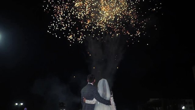 A couple in love looks at the fireworks.  The bride and groom look at the fireworks. Fireworks festival.