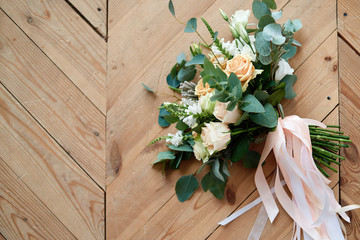 Big bridal bouquet of pink roses and greenery with satin ribbons on wooden background, copy space. Wedding concept. Top view, flat lay