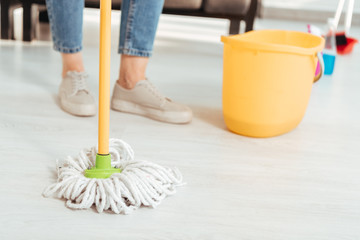 Cropped view of woman cleaning floor with mop
